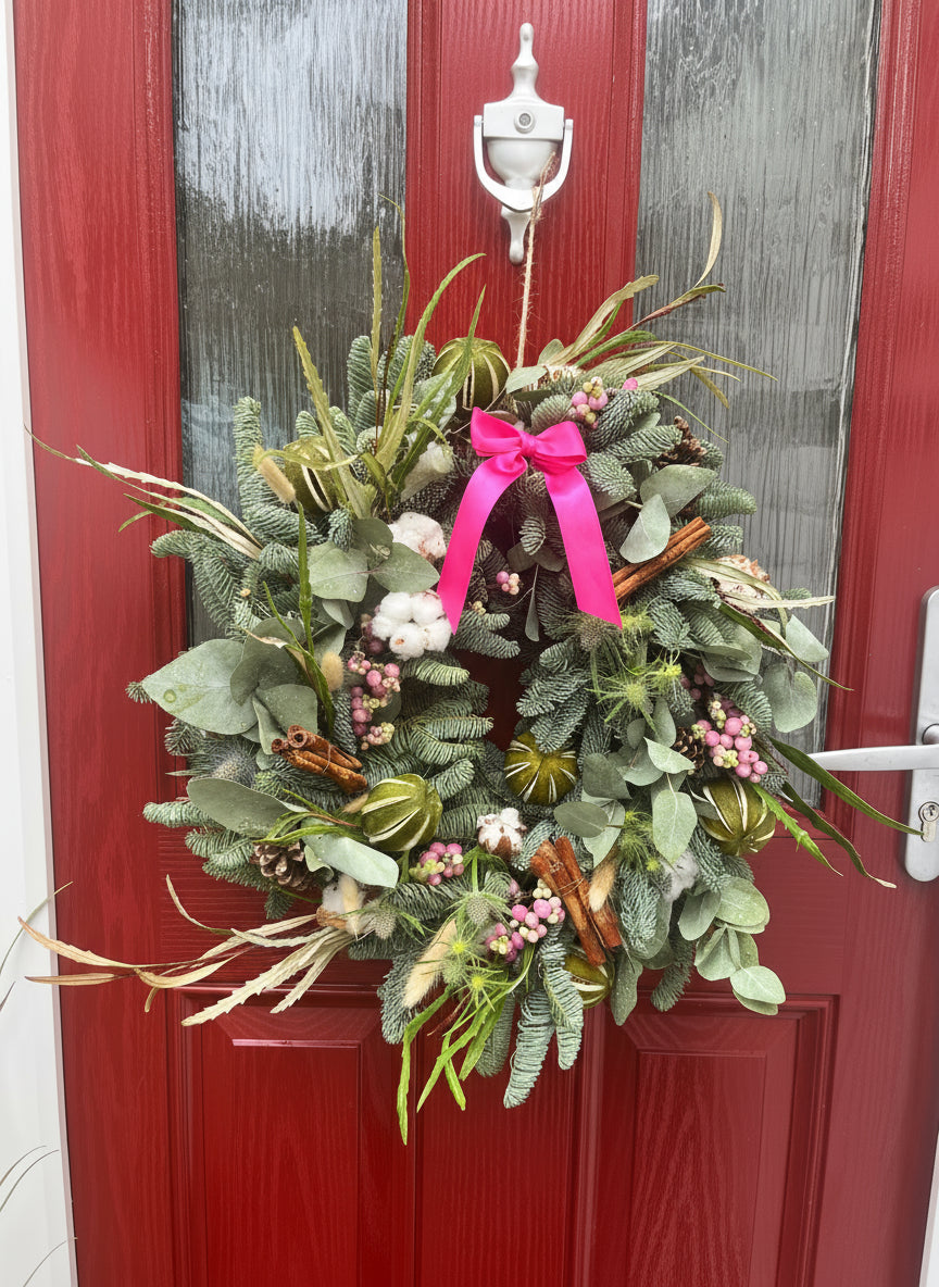 Decorative wreath with a pink bow on a red door