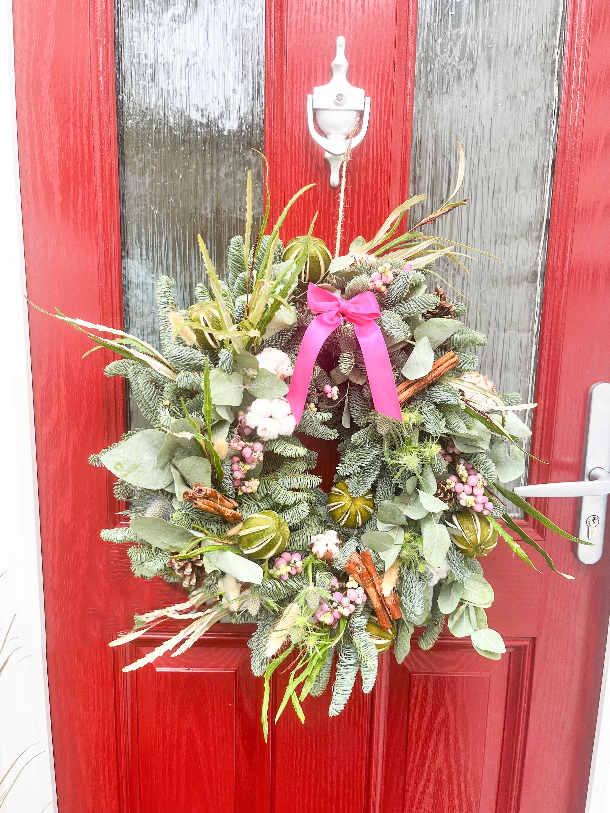 Green wreath with pink ribbon on a red door