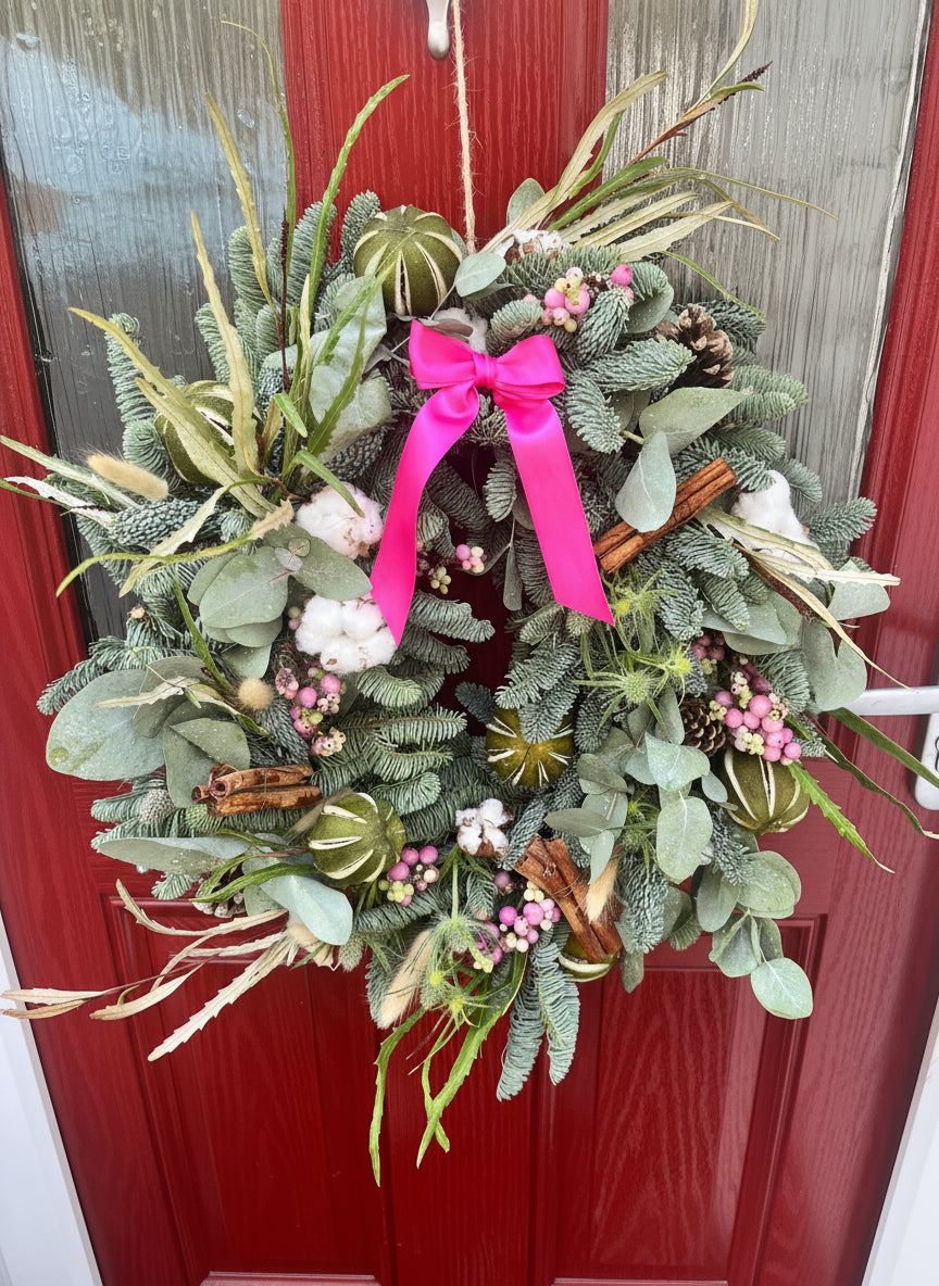 Decorative wreath with a pink ribbon on a red door