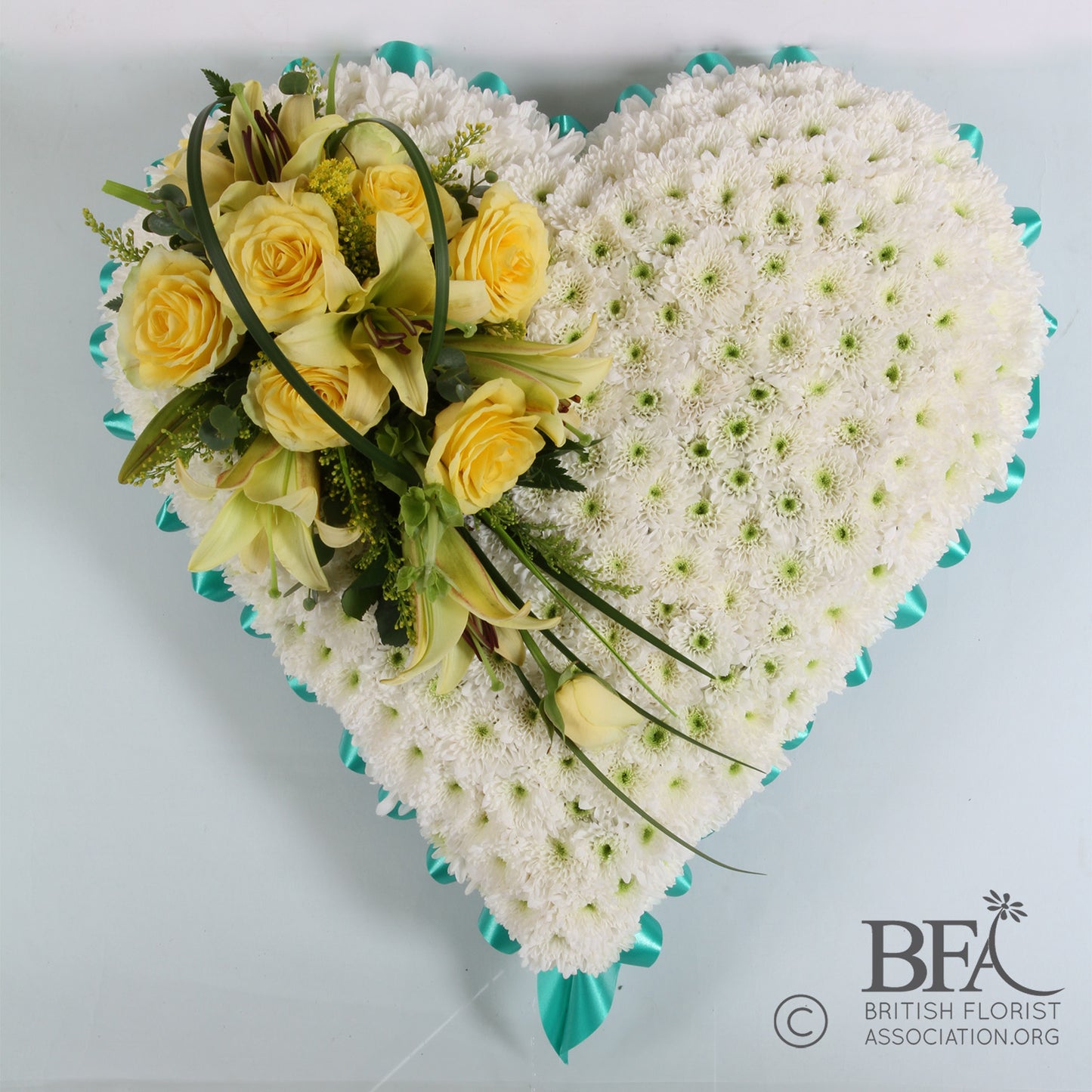 A beautiful hand-crafted chrysanthemum closed heart with roses, lilies, and delicate foliage.