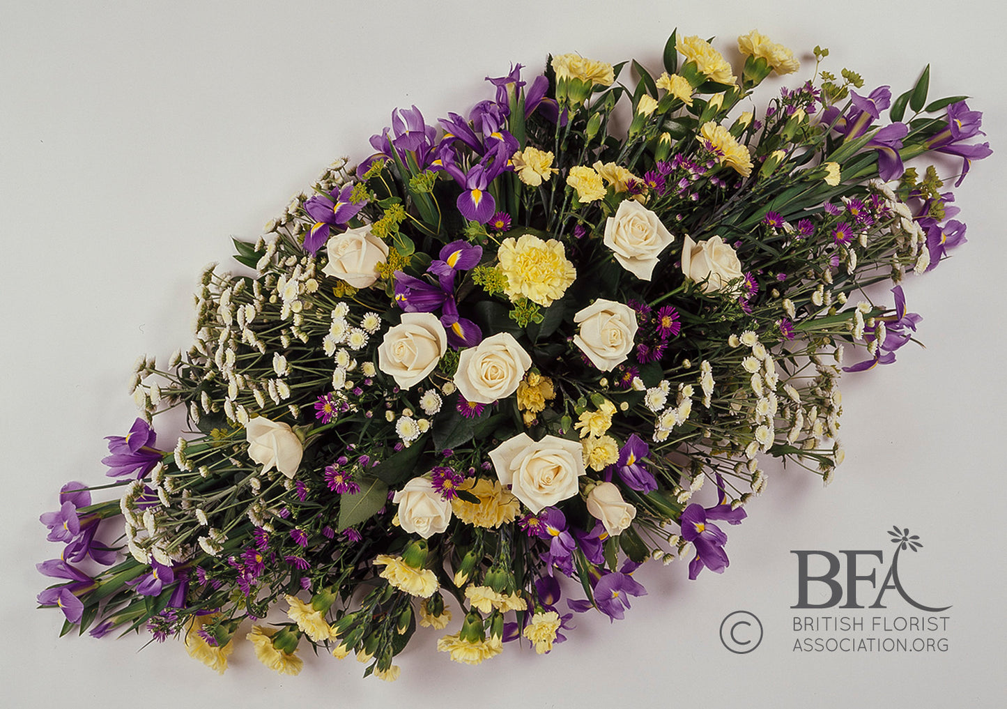 Elegant double ended funeral spray with white roses, blue iris, yellow flowers, and carnations, handcrafted in Stevenage for a meaningful tribute.