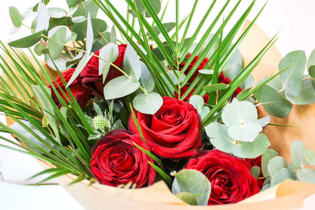 A classic floral bouquet featuring vibrant red roses and fresh eucalyptus.