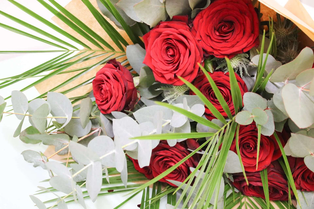 Elegant red roses nestled among aromatic eucalyptus leaves, making a stunning floral gift