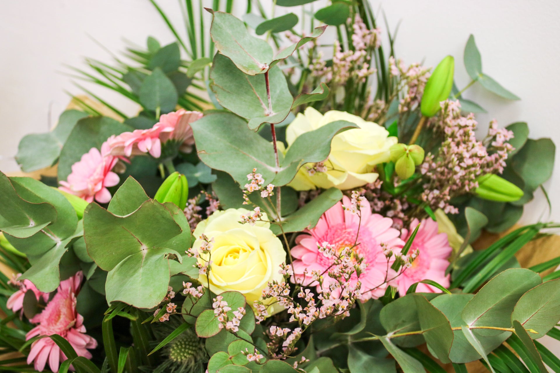 Close-up of roses, gerberas, pink limonium, and eucalyptus in The Sophia bouquet

