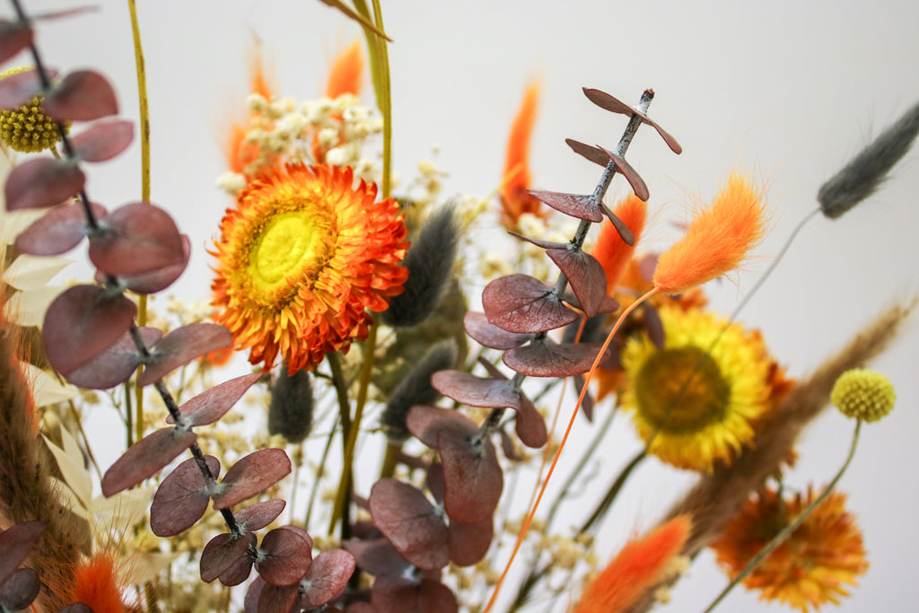 Autumn dried bouquet with orange flowers, including red eucalyptus and fall blooms