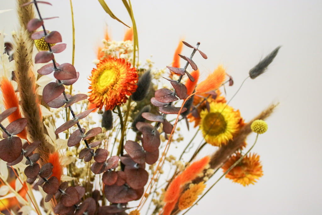 Autumn dried bouquet featuring orange roses, red eucalyptus, and warm autumnal tones