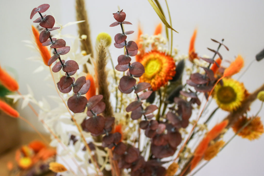 Gorgeous autumn dried flower bouquet with orange dried flowers and red eucalyptus