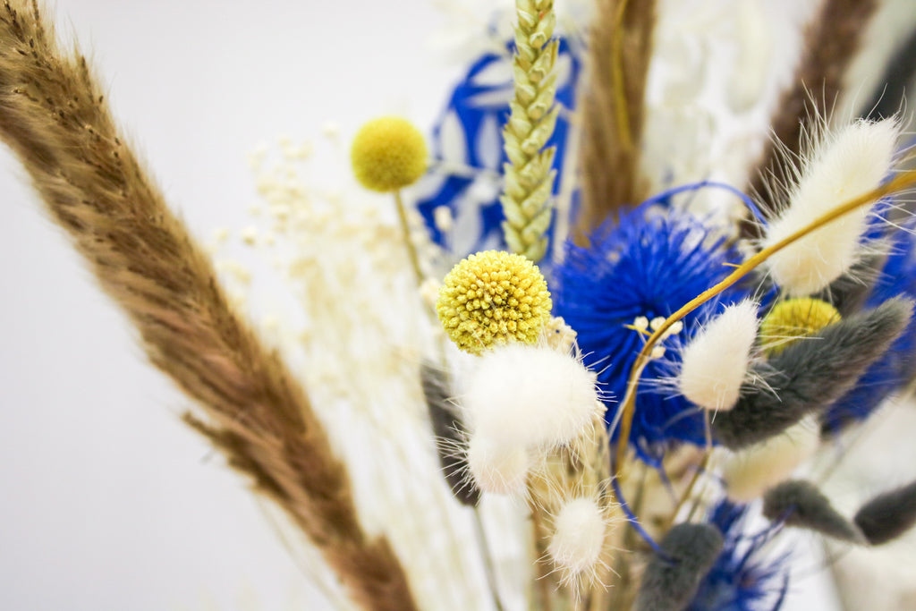 Vibrant blue and yellow dried flower arrangement featuring pampas grass, perfect for adding a bright, bohemian touch to weddings, events, or home decor.