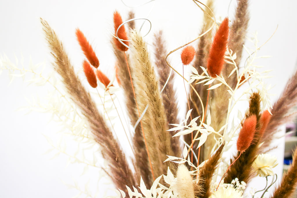 Boho pampas bouquet with a combination of dried pampas grass, wildflowers, and foliage, perfect for rustic wedding decorations or home styling.