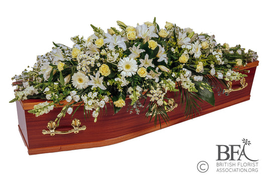 Classic white and cream full-length coffin spray with roses, lilies, and seasonal foliage.