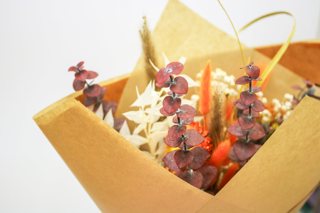 Dried fall bouquet with orange roses, red eucalyptus, and autumn dried flowers