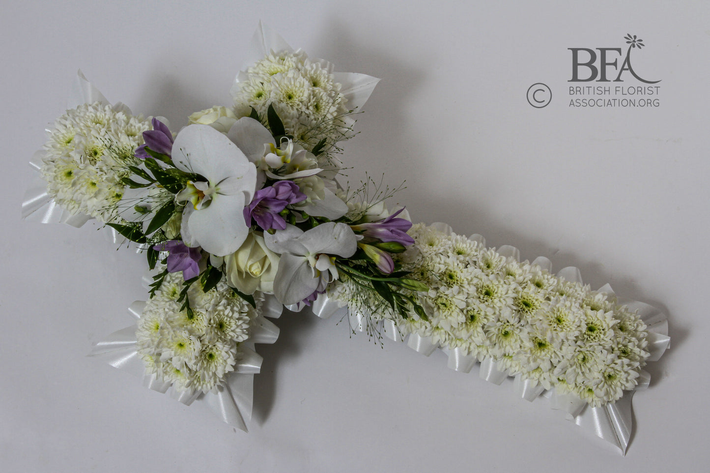 A beautiful funeral cross tribute crafted with fresh flowers such as roses, lilies, and chrysanthemums, symbolizing faith and remembrance.