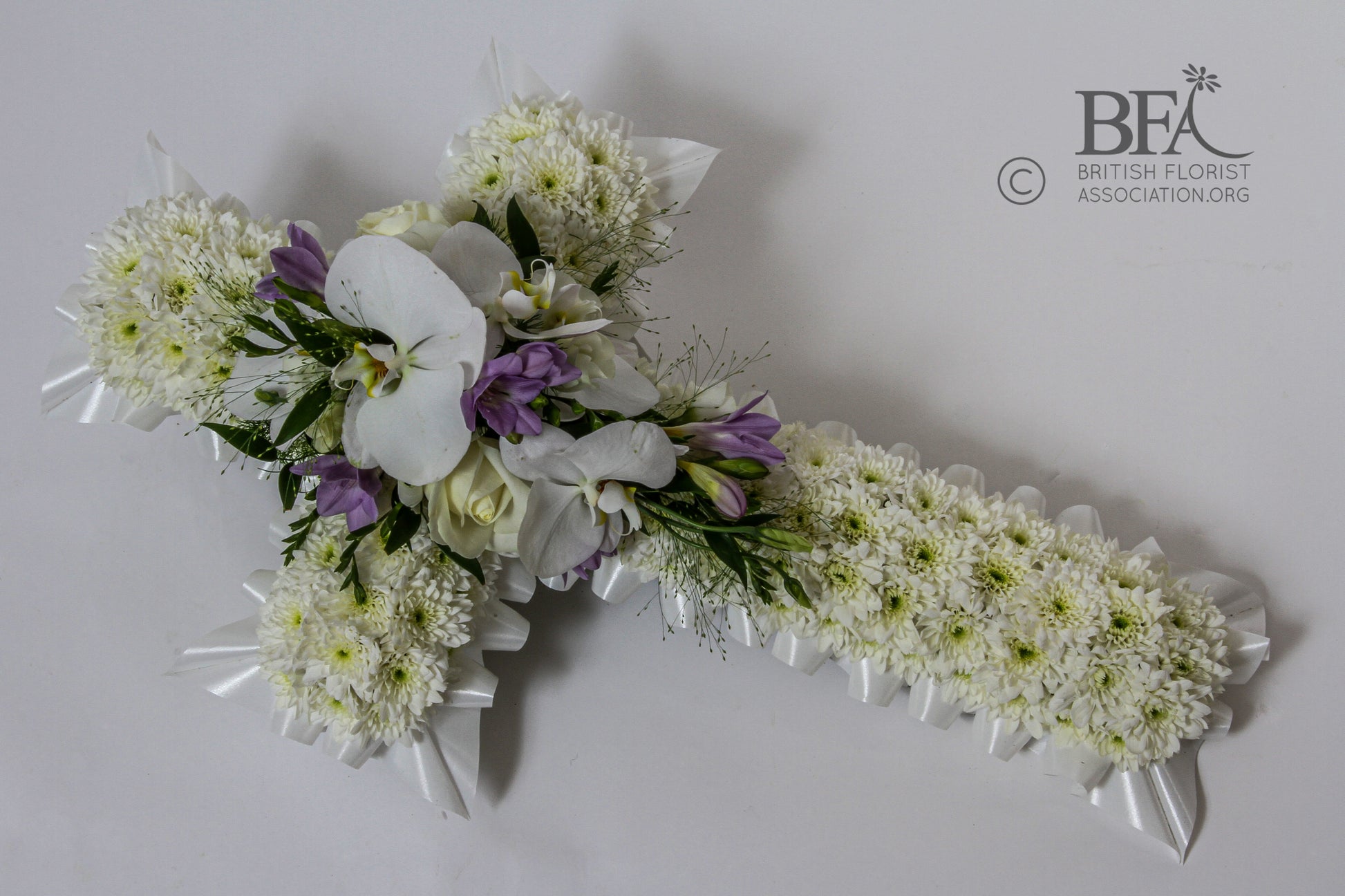 A beautiful funeral cross tribute crafted with fresh flowers such as roses, lilies, and chrysanthemums, symbolizing faith and remembrance.