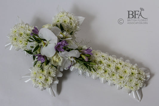 A beautiful funeral cross tribute crafted with fresh flowers such as roses, lilies, and chrysanthemums, symbolizing faith and remembrance.