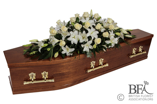  A serene and elegant lily casket spray, featuring beautiful white lilies, complementing greenery, and delicate seasonal blooms, a tribute of peace and remembrance.