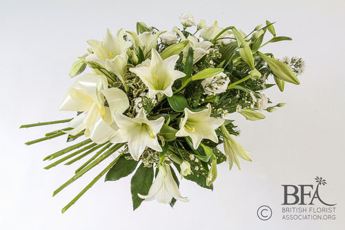 A graceful lily spray with fresh white lilies, delicate foliage, and complementary blooms, symbolizing purity and peace in a respectful funeral tribute.