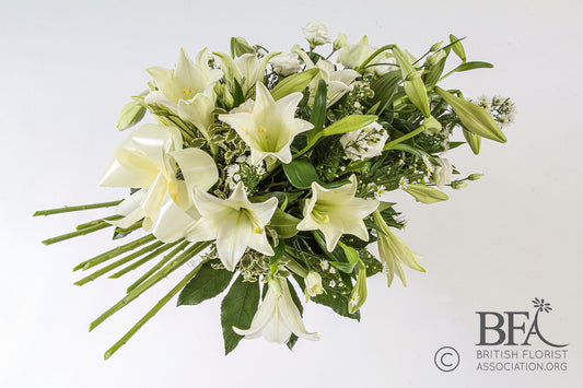  A graceful lily spray with fresh white lilies, delicate foliage, and complementary blooms, symbolizing purity and peace in a respectful funeral tribute.