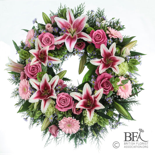 Elegant funeral wreath featuring white lilies and soft pink roses, arranged in Stevenage with care and seasonal foliage.