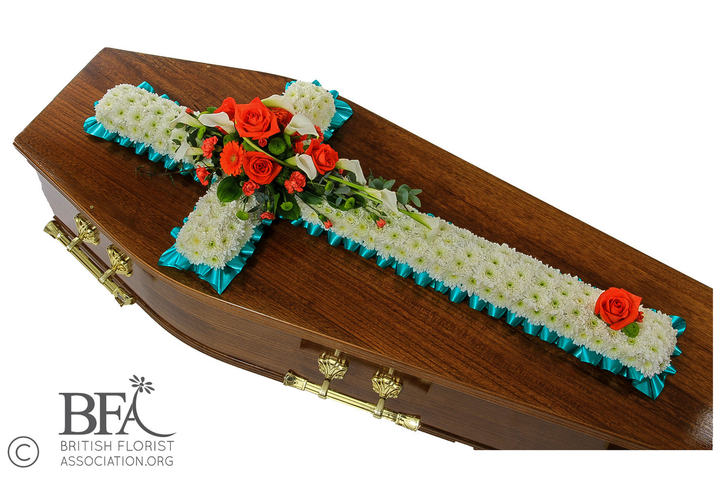 A massed cross tribute with chrysanthemums and a selection of orange flowers on top, symbolizing remembrance.