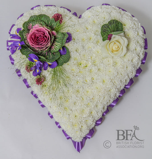 A feminine massed heart tribute with a base of chrysanthemums, delicately spray of blooms on top.

