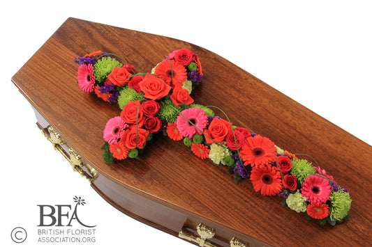  A hand-crafted open cross tribute, featuring gerberas, roses, chrysanthemums, and carnations in vibrant colors.