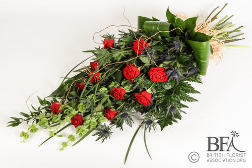 A stunning red rose sheaf, featuring long-stemmed red roses and mixed foliage, thoughtfully crafted in Stevenage as a beautiful and elegant tribute.