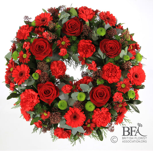 A vibrant red roses wreath adorned with carnations, gerbera, and seasonal greenery, thoughtfully arranged in Stevenage to create a striking and heartfelt funeral tribute.