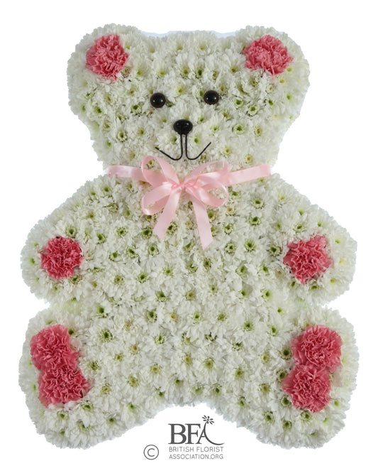 A heartfelt teddy bear tribute with a chrysanthemum base and delicate pastel flowers.