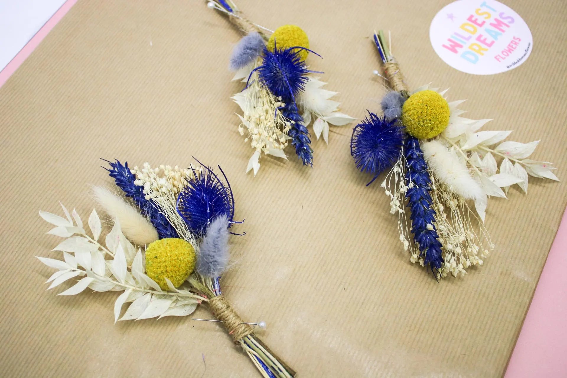 Vibrant yellow and blue buttonhole flower featuring a blend of dried blooms and greenery, perfect for adding a pop of colour to weddings or special events. A charming boutonnière for grooms, groomsmen, or a unique floral accessor