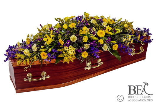 A colorful double-ended spray of yellow and blue flowers, including lilies, roses, carnations, and irises.

