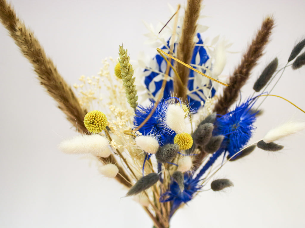 A beautiful yellow and blue dried wedding bouquet with pampas grass and other preserved flowers, perfect for adding a rustic yet elegant touch to your wedding day.