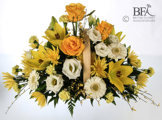  A vibrant basket arrangement of yellow roses, lilies, and cream gerbera, offering a lively tribute.

