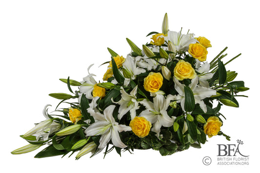  A vibrant yellow and white single-ended spray, featuring roses, carnations, and seasonal foliage.

